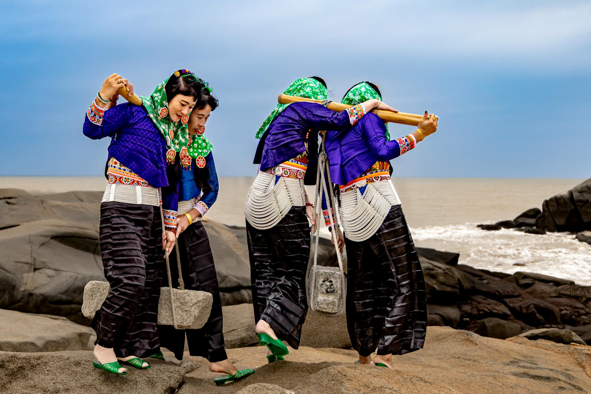Kobiety w barwnych strojach ludowych tańczą na skalistym wybrzeżu