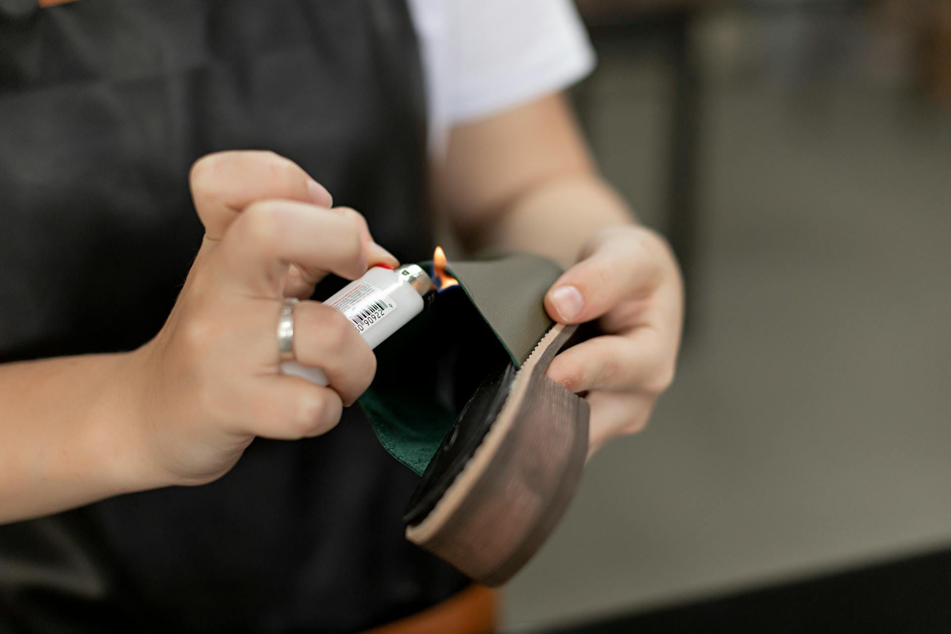 Ręce szewca przy naprawie podeszwy buta ogniem z zapalniczki