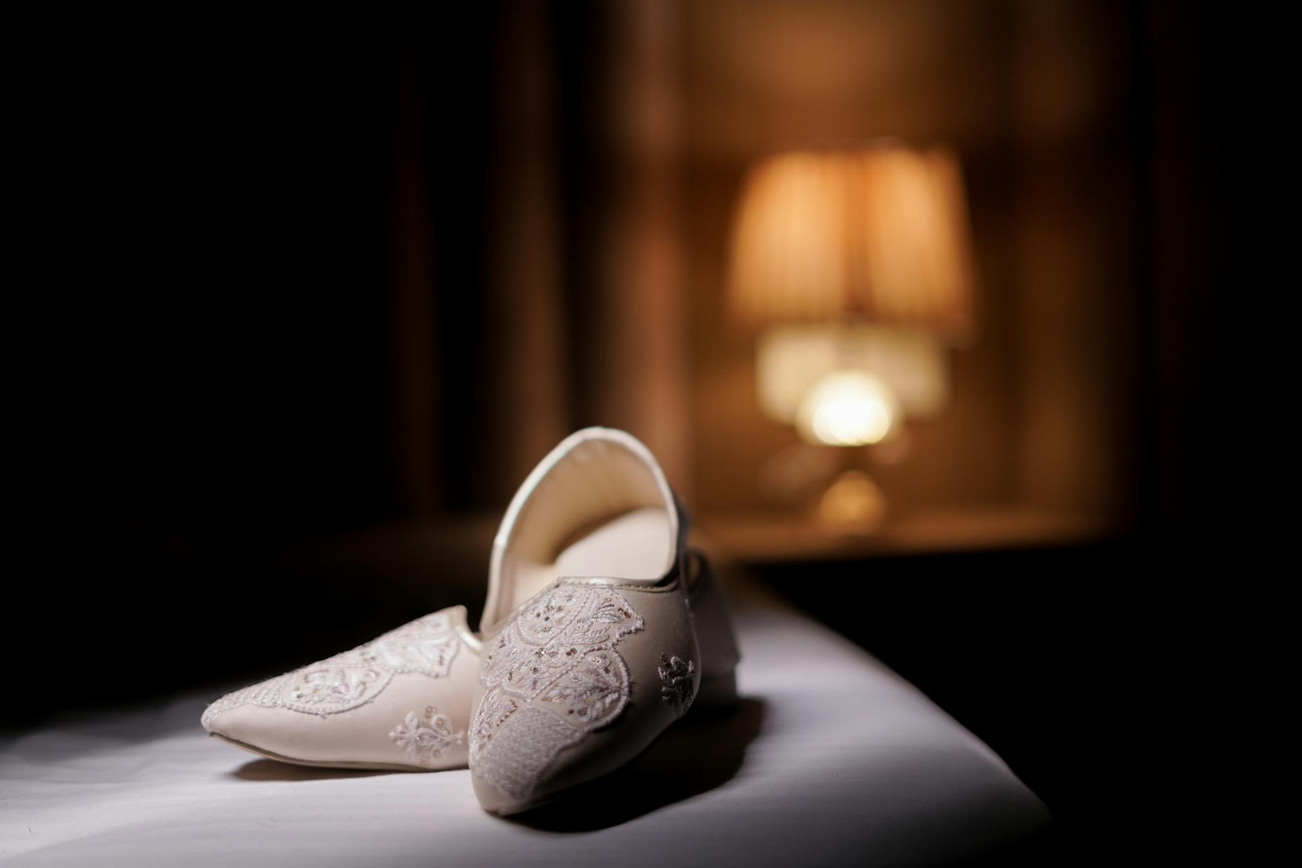 Zdobione indyjskie jutty ślubne w ciepłym świetle lampy