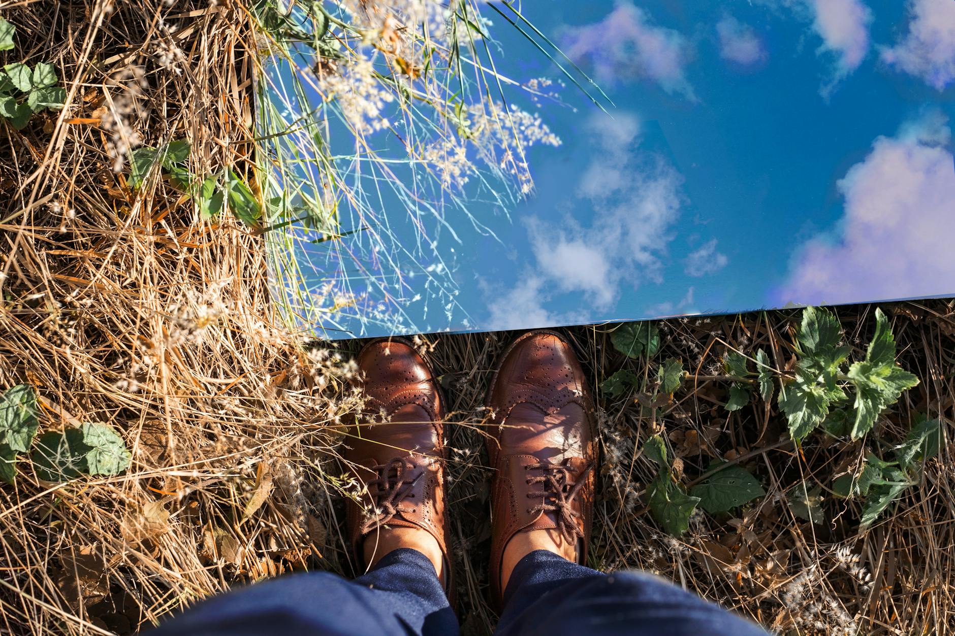 Brązowe skórzane buty odbijające błękitne niebo w lustrze na zewnątrz