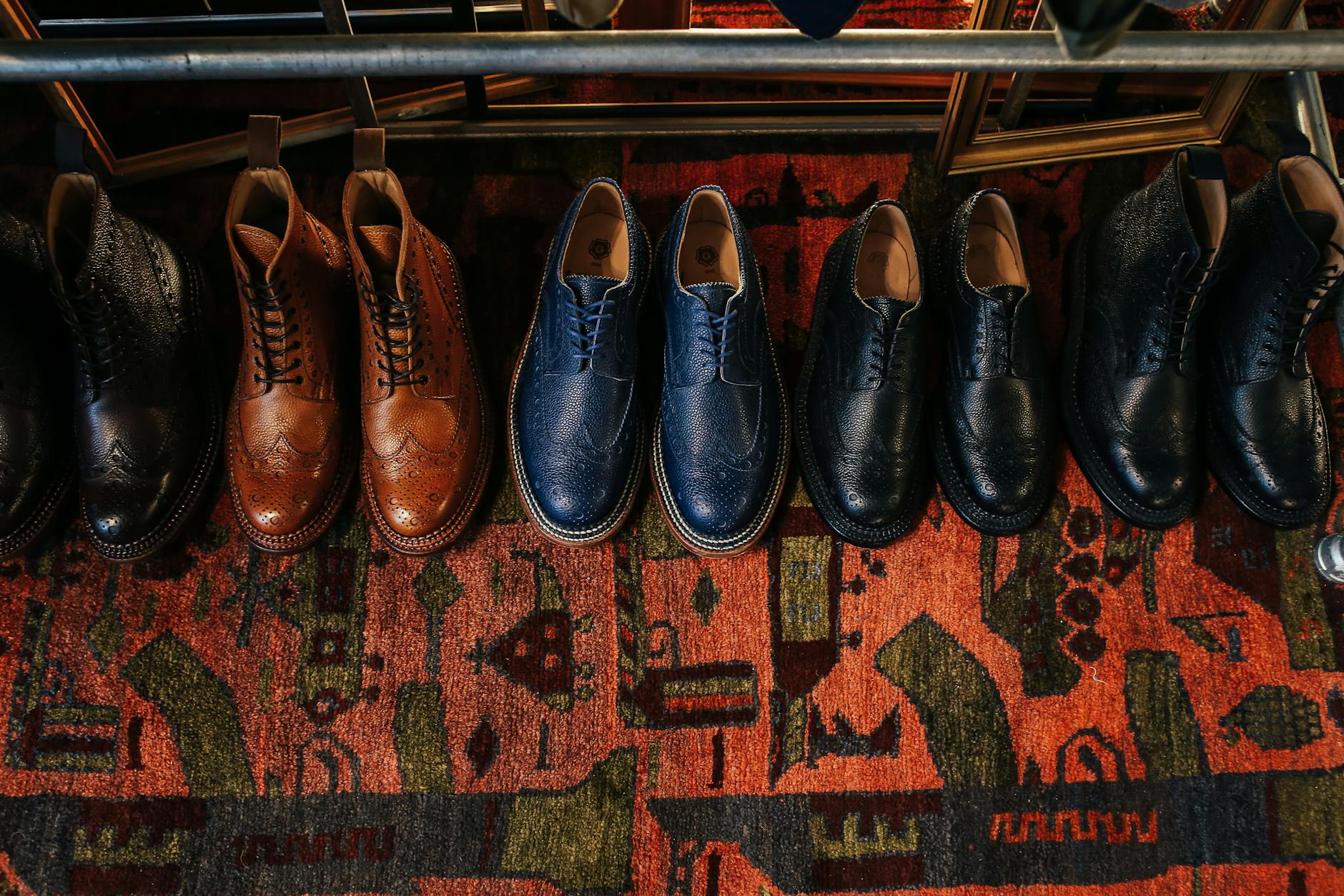 Klasyczne skórzane buty ułożone na kolorowym, wzorzystym dywanie vintage