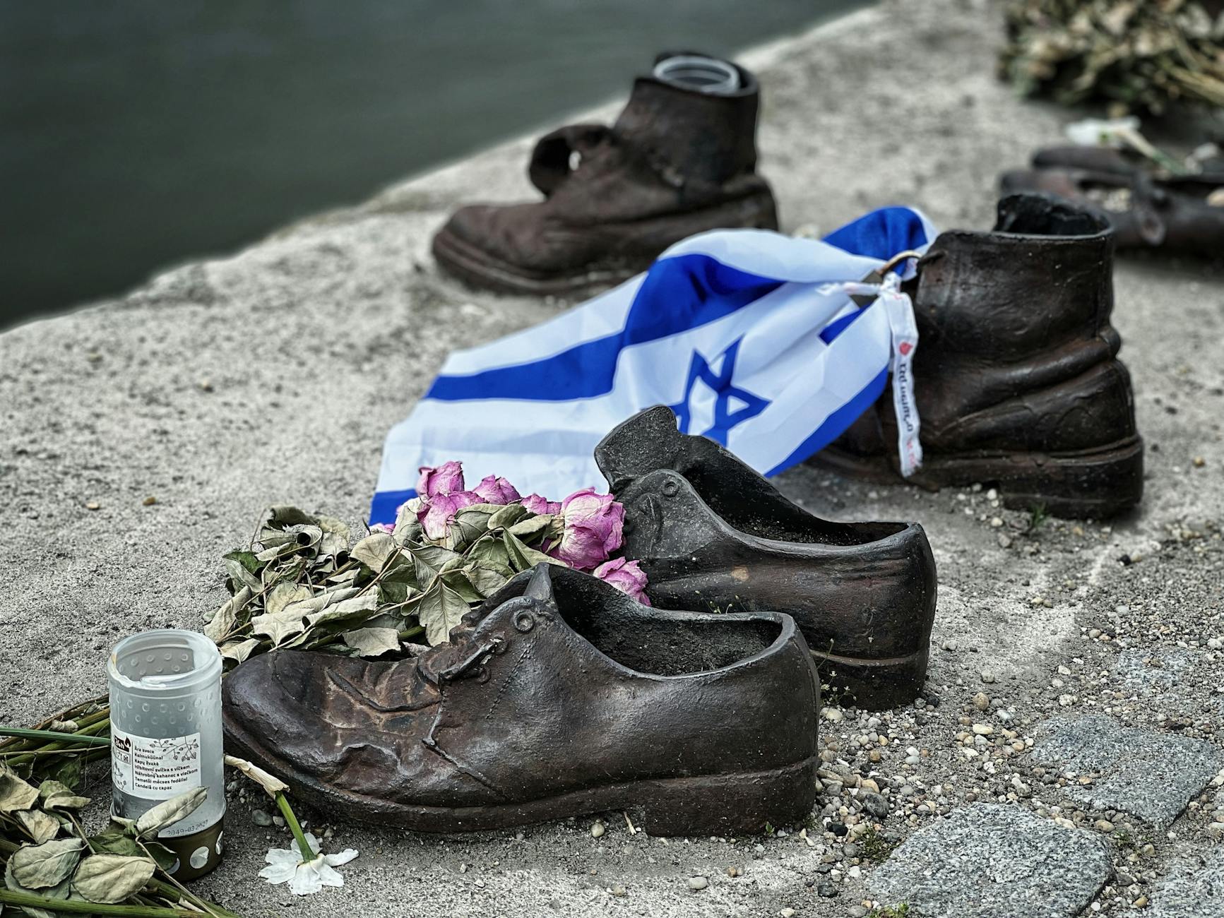 Rzeźba butów z flagą Izraela i kwiatami na brzegu rzeki