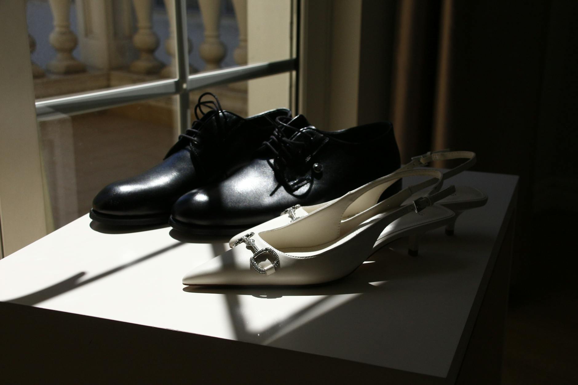 Eleganckie czarne męskie i białe damskie buty w słońcu przy oknie