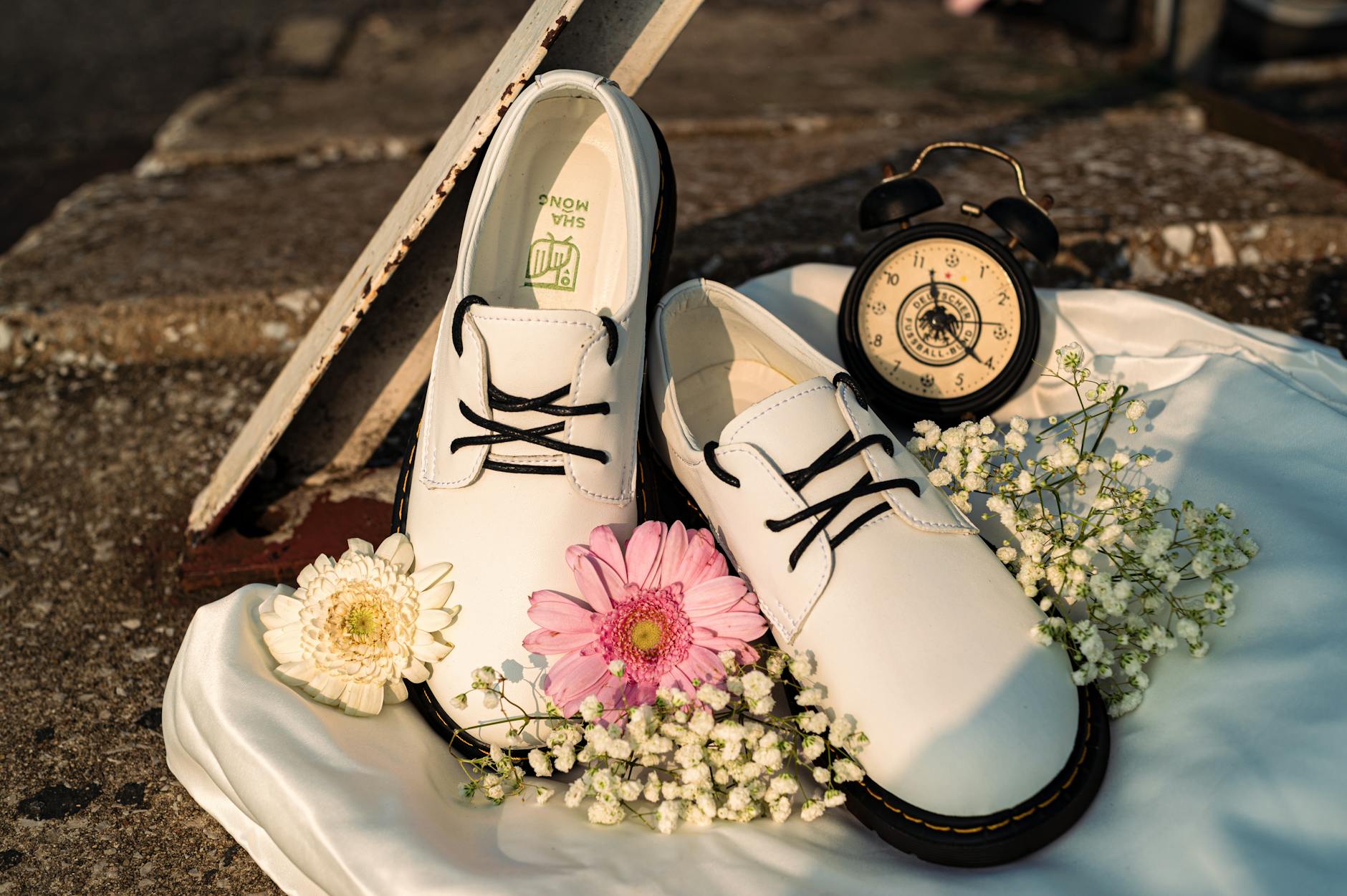 Nowoczesne białe buty wśród kwiatów obok zabytkowego zegara