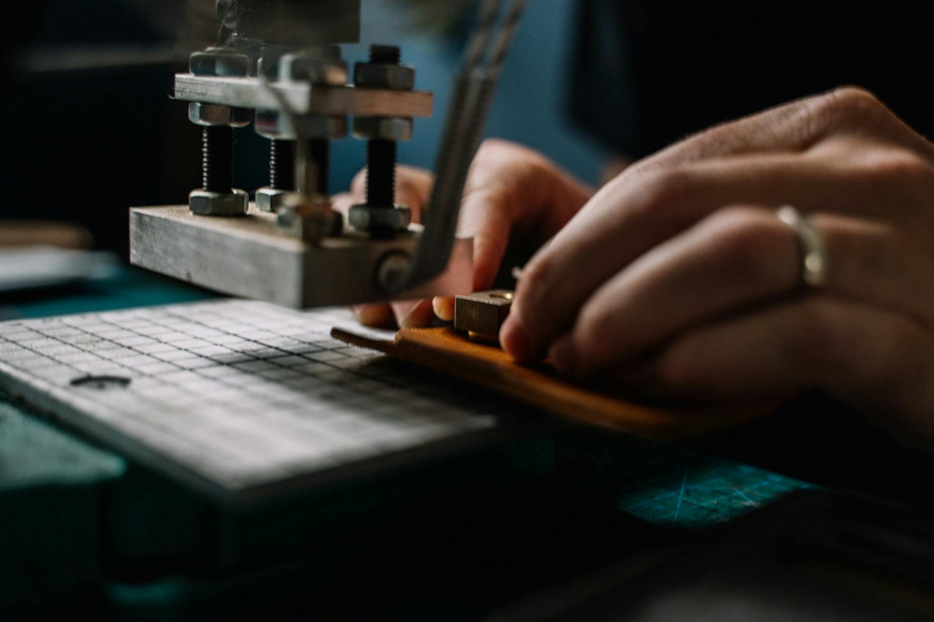 Rzemieślnik z metalowymi narzędziami przy pracy nad skórzanym pantoflem