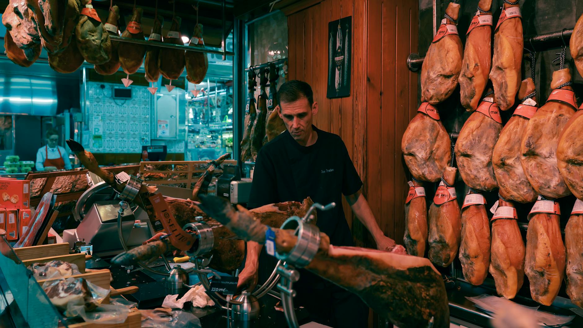 Sprzedawca kroi szynkę iberyjską w tradycyjnym markecie w Barcelonie