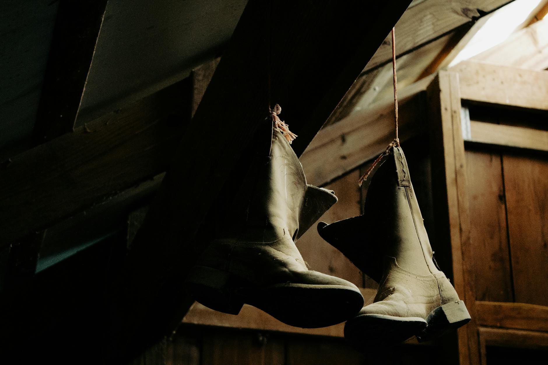Stare kowbojki wiszące w słabo oświetlonej, drewnianej stodole